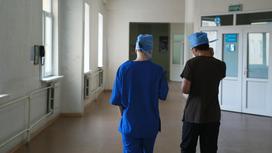 Медперсонал в форме, со спины, идут по коридору больницы