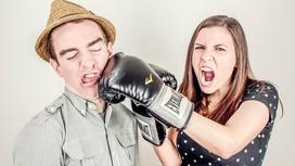 Девушка в боксерских перчатках бьет парня по лицу