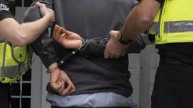 Задержанного мужчину в наручниках ведут полицейские