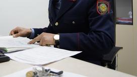 Полицейский сидит за столом и изучает бумаги