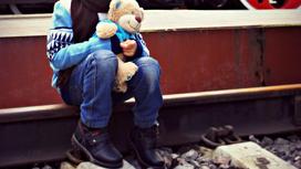 Ребенок сидит на железнодорожных путях