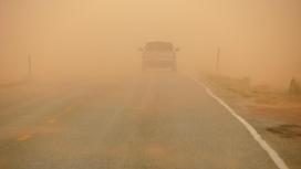 Машина едет по дороге во время пыльной бури