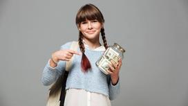 Девушка с косичками указывает на банку с долларовыми купюрами