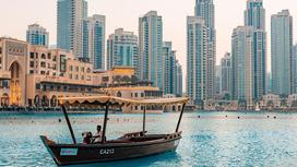Деревянная лодка, проплывающая по воде на фоне небоскребов Дубая