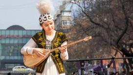 Девушка из Казахстана в национальной одежде играет на домбре