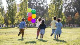Дети бегают на улице с воздушными шарами
