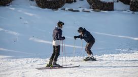 Два человека катаются на лыжах
