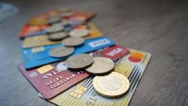 Банковские карты и монеты тенге лежат на столе