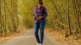 Беременная женщина стоит на дороге
