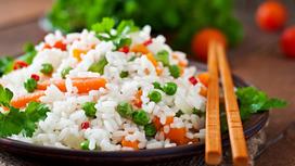 На сервировочной тарелке рассыпчатый рис с овощами