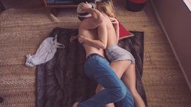 Парень и девушка обнимаются, лежа на полу
