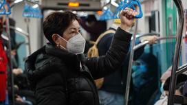 Женщина в маске едет в метро