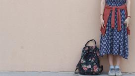 Девушка стоит рядом с рюкзаком
