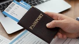 Мужская рука держит паспорт в обложке, в который вставлены два билета на самолет