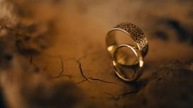 Золотые обручальные кольца на потрескавшемся грунте