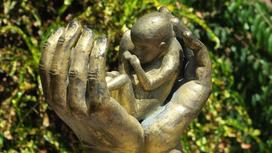 Статуя рук, держащих младенца