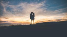Мужчина и женщина обнимаются на фоне заката