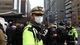 Южнокорейский полицейский держит в руках рацию