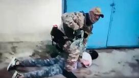 Задержанный мужчина лежит на земле, его держит сотрудник спецслужбы