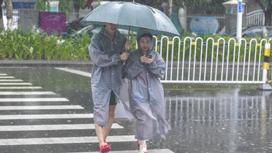 Люди переходят дорогу под дождем в Китае