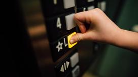 Человек нажимает пальцем на кнопку в лифте