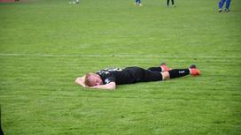 Футболист лежит на газоне