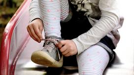 девочка завязывает шнурок на обуви