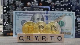 Кубики с надписью "crypto" стоят перед монетами биткоинов