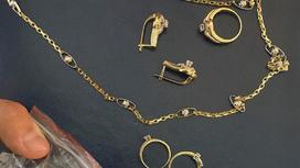 Золотые кольца, серьги и цепочка лежат на блокноте