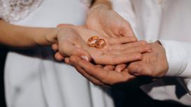 Женщина держит в руке обручальные кольца