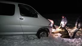 Мужчины пытаются вызволить застрявшее в снегу авто