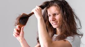 Девушка с трудом расчесывает сухие и спутанные волосы