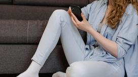 Девушка сидит на полу с телефоном в руках
