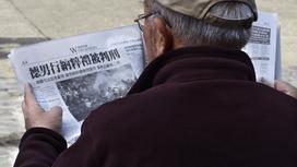 мужчина читает китайскую газету