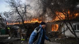 Мужчина пробегает перед горящим домом в Ирпене под Киевом