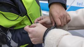 Полицейский одевает наручники на задержанную