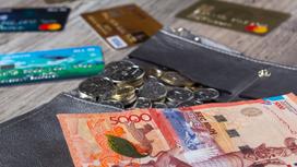 На столе лежат деньки, монеты и банковские карты