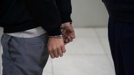 Мужчина в наручниках стоит в коридоре отделения полиции