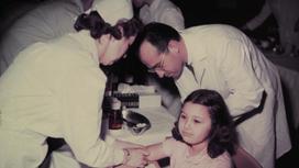 Доктор и медсестра вводят вакцину от полиомиелита школьнице