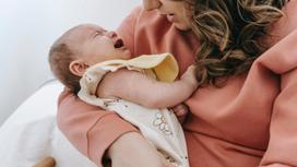Младенец плачет на руках у женщины