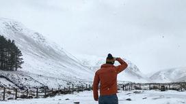 Мужчина стоит возле снежных гор