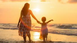 Мама с маленькой дочкой на пляже на закате