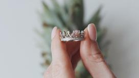 Между пальцами держат сербярное кольцо в виде короны