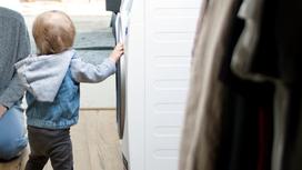 Ребенок стоит возле стиральной машины