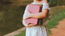 Девочка держит книги в руках