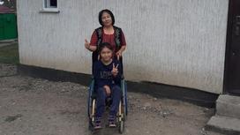 Женщина с дочерью-инвалидом стоит возле дома в Алматинской области