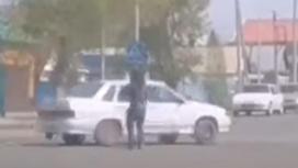 Женщина стоит на перекрестке перед белым автомобилем