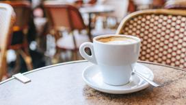 Чашечка кофе с блюдцем стоит на столике