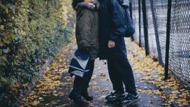 Двое школьников стоят на улице осенью