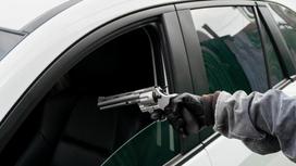 Мужчина целится пистолетом в сиденье водителя